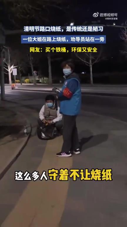 清明期間，一位大姐路上燒紙，勸導(dǎo)員一旁站立