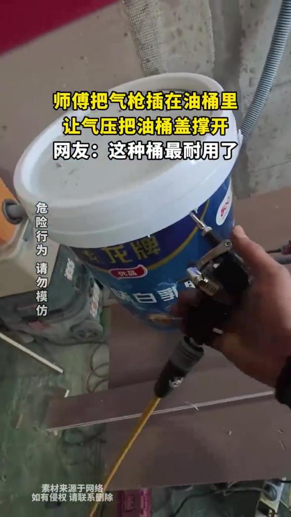 师傅把气枪插在油桶里，让气压把油桶盖撑开