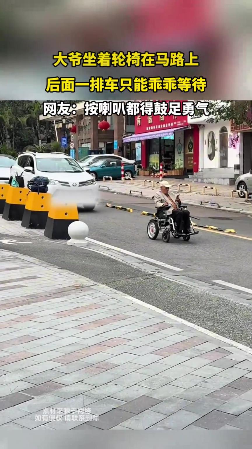 大爺坐著輪椅在馬路上，后面一排車只能乖乖等待