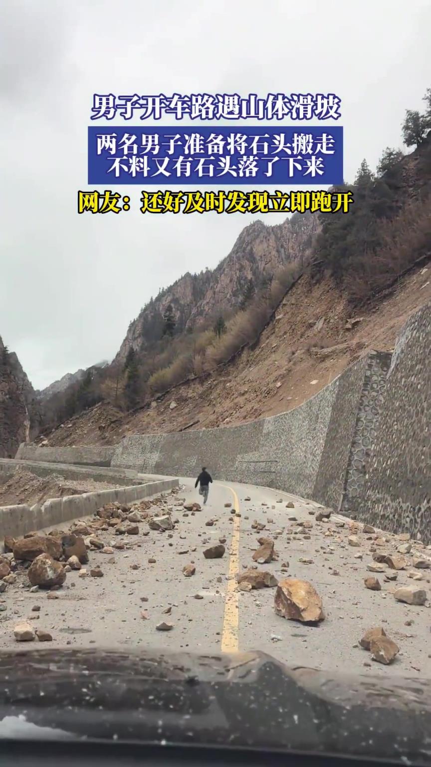 男子开车路遇山体滑坡，两名男子准备将石头搬走