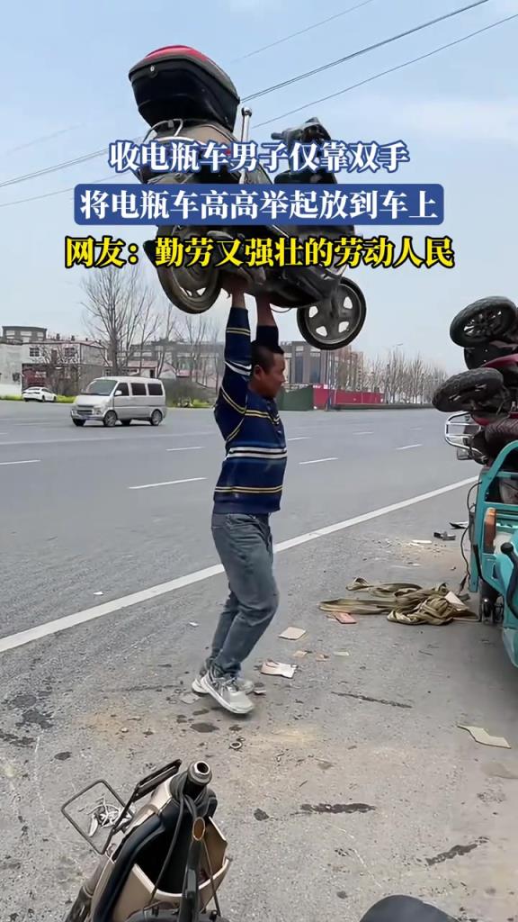收电瓶车男子仅靠双手 将电瓶车高高举起放到车上