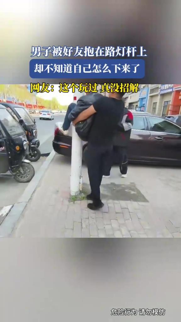 男子被好友抱在路灯杆上，却不知道自己怎么下来了