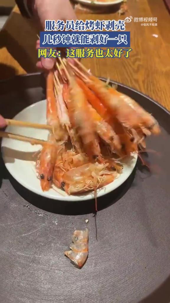 服務(wù)員給烤蝦剝殼，幾秒鐘就能剝好一只