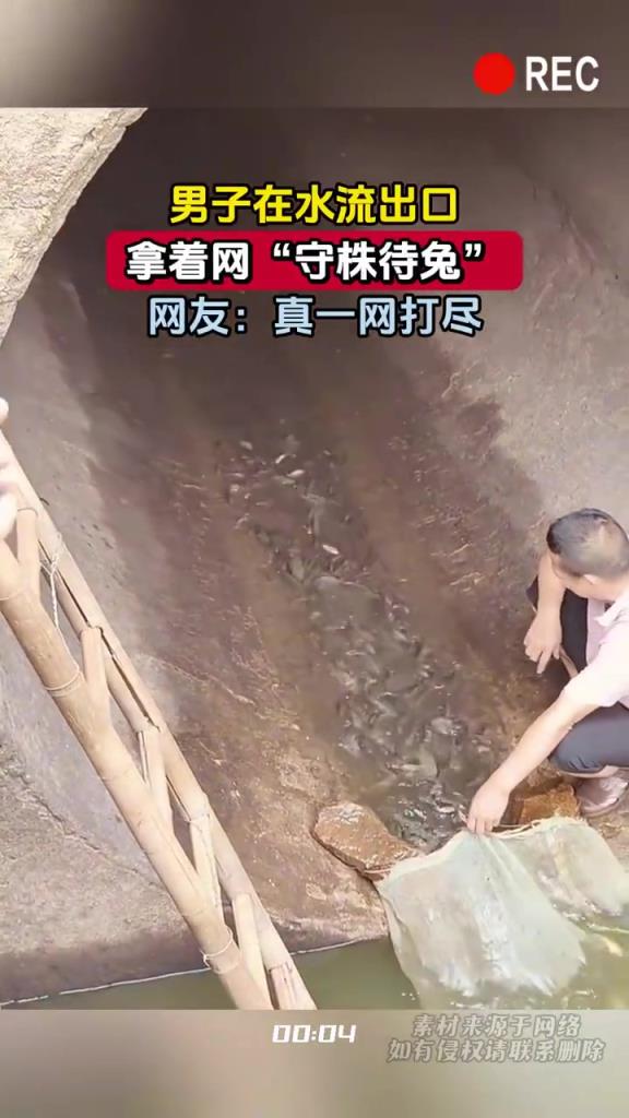 男子在水流出口，拿著網(wǎng)“守株待兔”