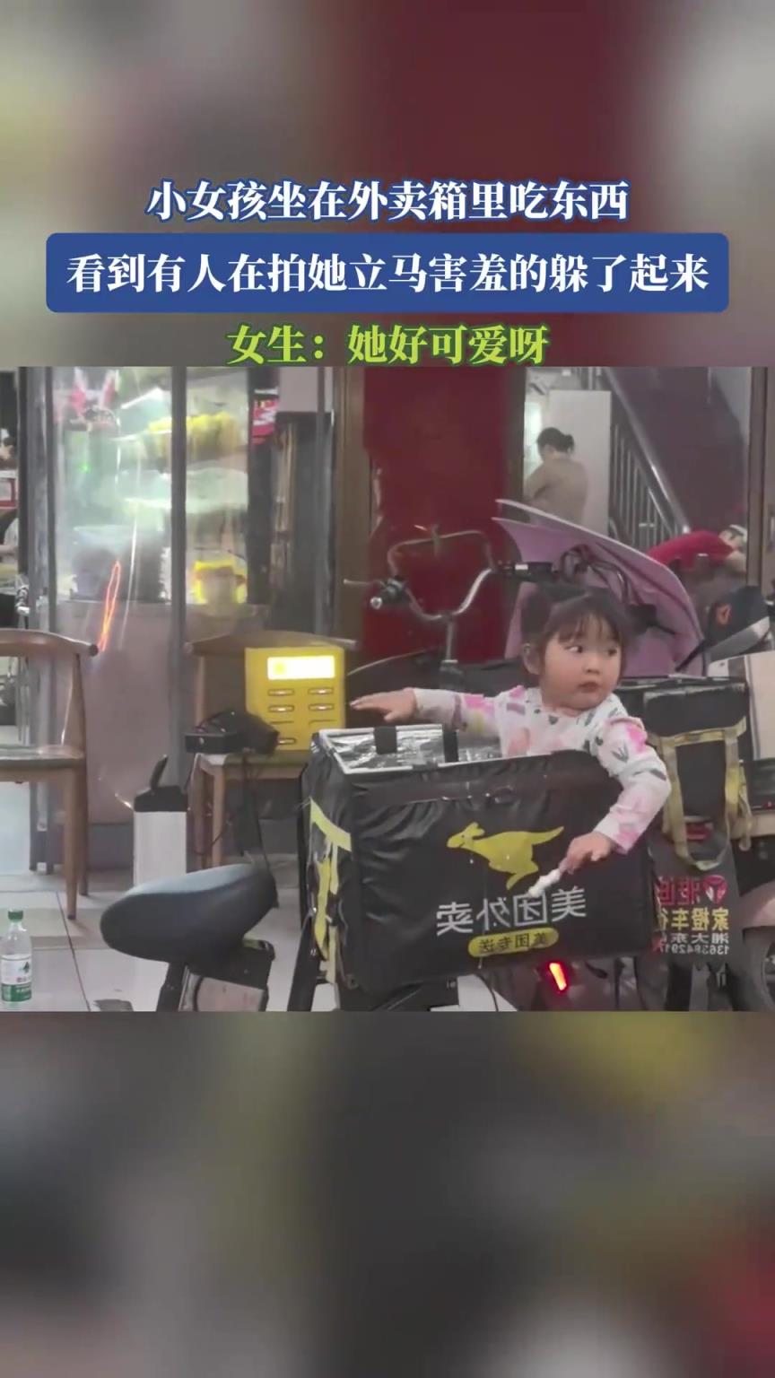 小女孩坐在外賣箱里吃東西，看到有人在拍她立馬害羞的躲了起來(lái)