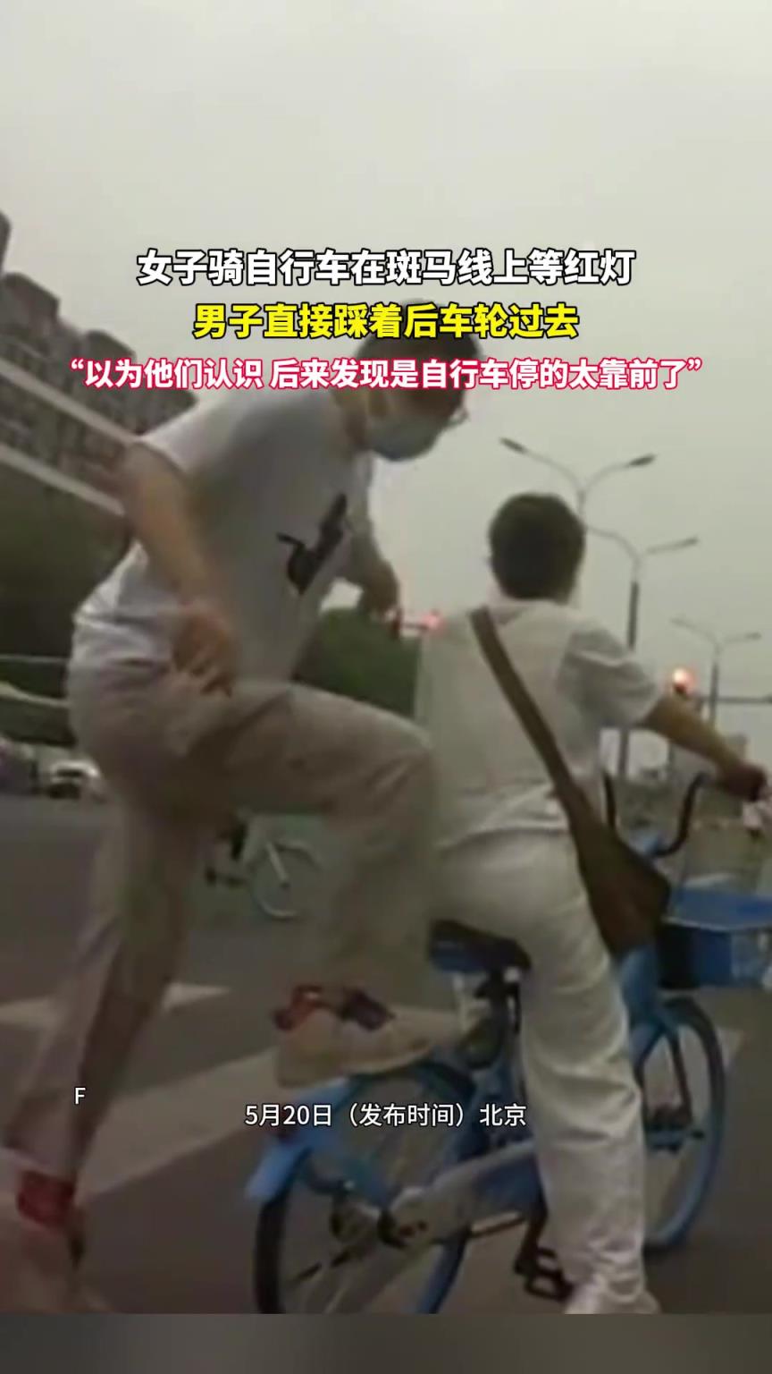 女子騎自行車在斑馬線上等紅燈 男子直接踩著后車座過去
