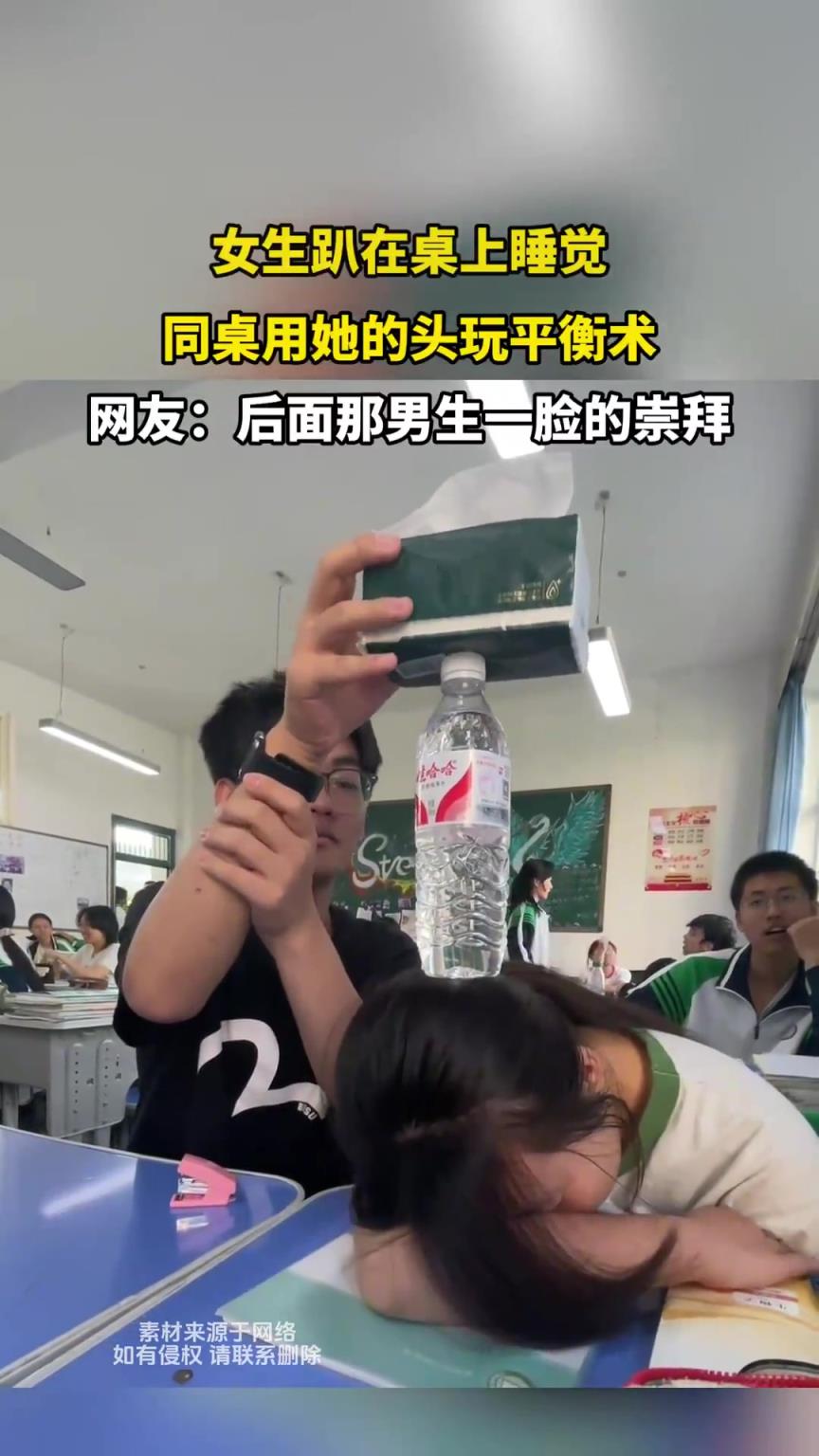 女生趴在桌上睡覺，同桌用她的頭玩平衡術(shù)