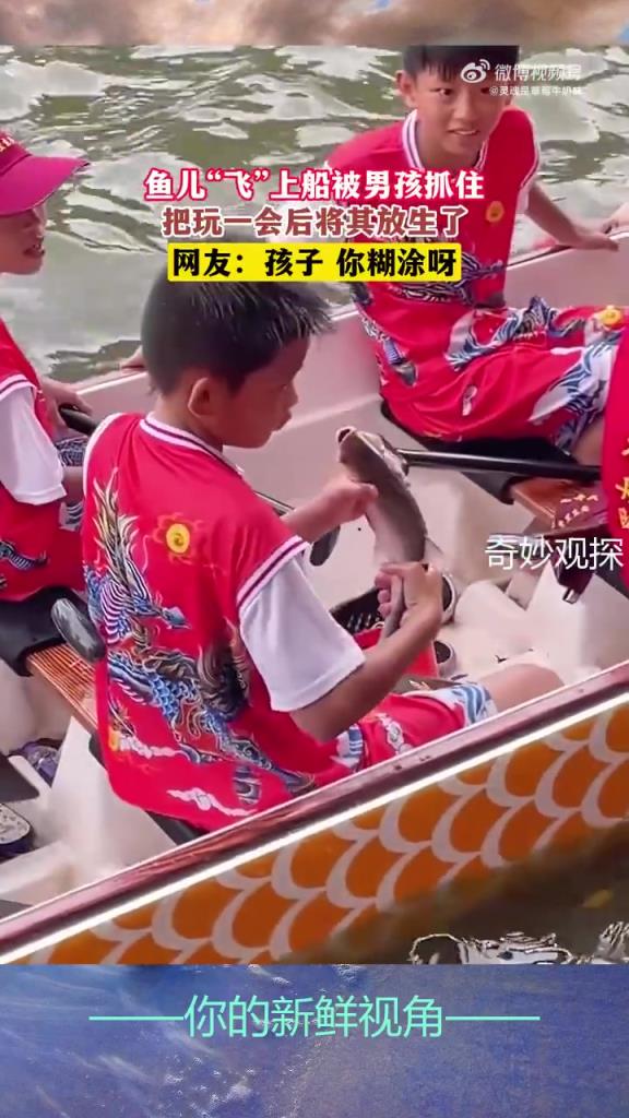 鱼儿“飞”上船被男孩抓住，把玩一会后将其放生了