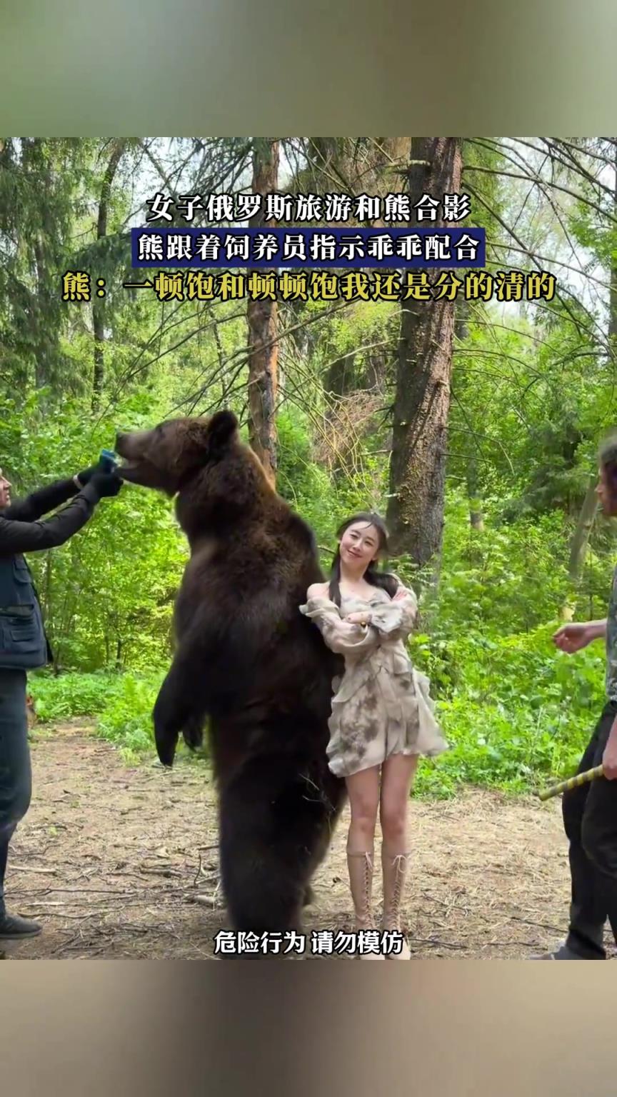 女子俄罗斯旅游和熊合影，熊跟着饲养员指示乖乖配合