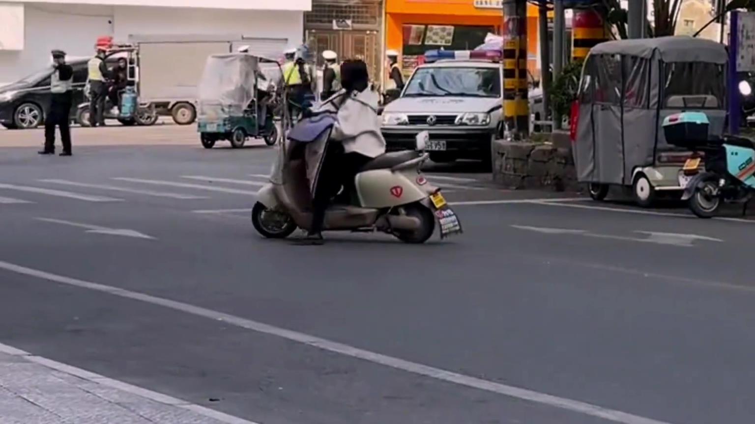 女子街上骑行遇查车，因未佩头盔掉头溜走碰到他车